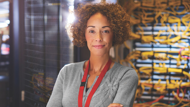 Woman smiling at viewer, standing in front of shelves filled with products in a warehouse-like setting